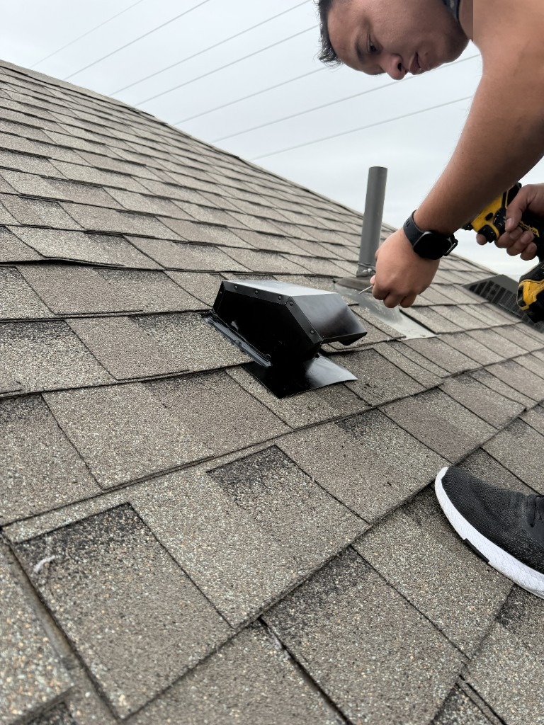 Technician drilling a black roof vent into place