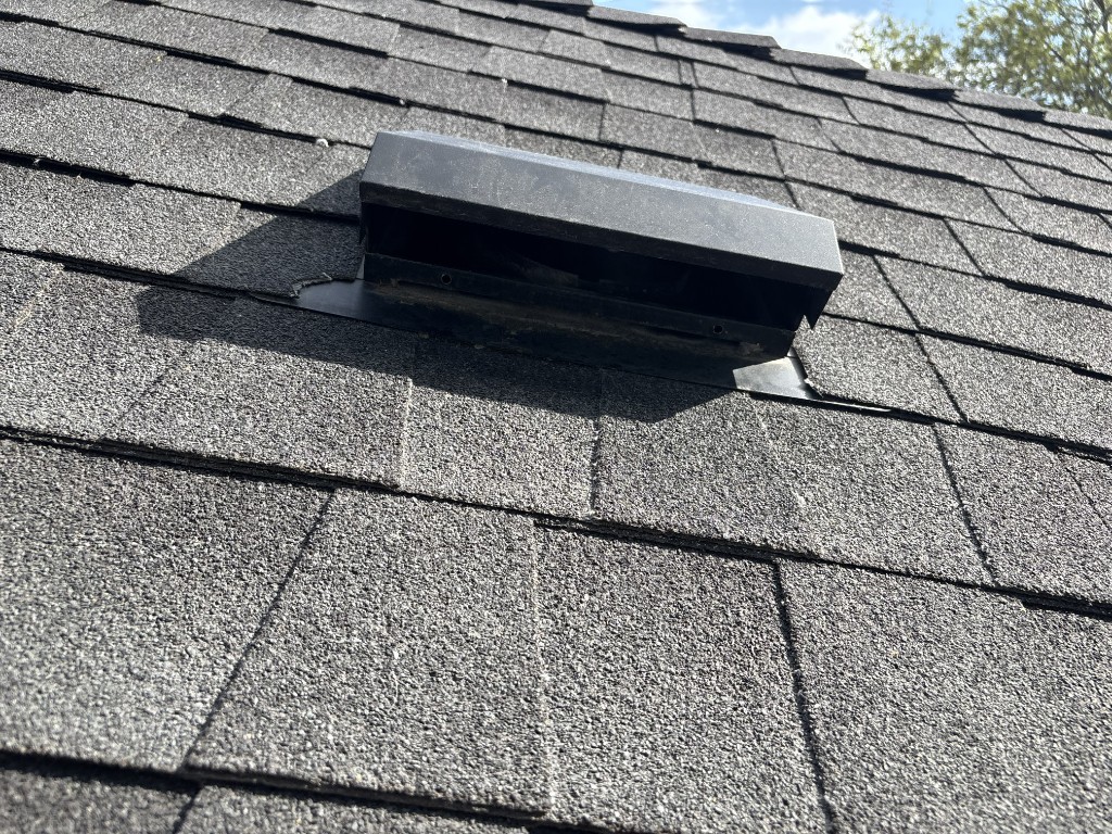 Black roof vent seated on gray asphalt shingles