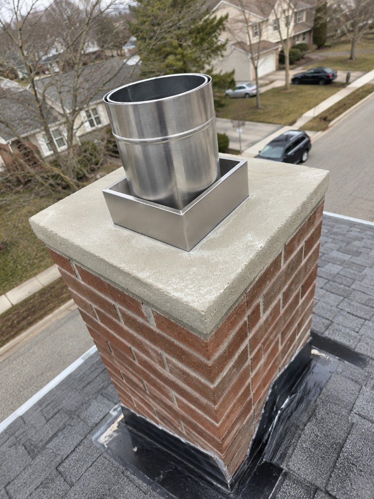 Stainless chimney flue seated on a brick chimney crown
